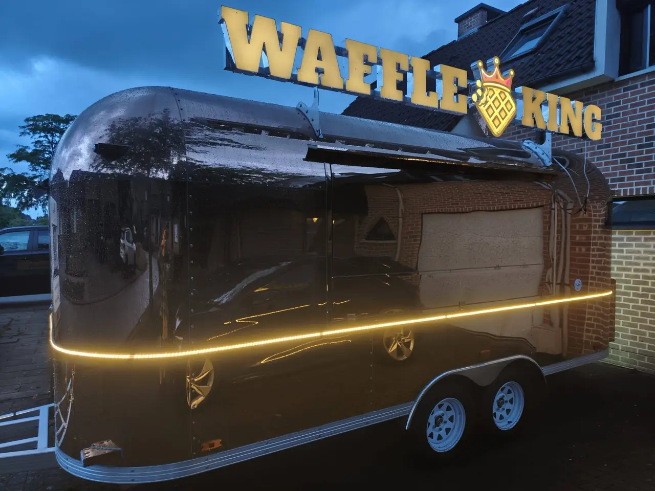 De nieuwe WaffleKing foodtruck, een zwarte koets met verlichte naamletters